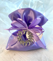 Bomboniera Sacchetto in raso lilla (glicine) con applicato ciondolo corona alloro in metallo completo di aurea a forma di confetti, nastri e bigliettino stampato

Dimensione ciondolo corona alloro: dm 4.

Sacchetto lilla come bomboniera per la laurea indirizzo Lingue.

Possibilità di modificare il colore del sacchetto o nastrini in base all'indirizzo di Laurea.